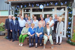 Gruppenfoto vor der Saaltür mit grünen, geschmückten Kranz