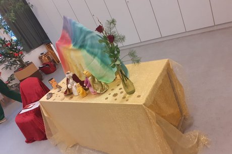 Krippe Das Bild zeigt eine Krippe aus Holzfiguren. Das Ensemble steht auf einem Tisch.