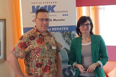 Der Vorsitzende Rico Zellin und die Referentin Diana Meyer stehen vor einem Aufsteller des VdK Sozialverbandes OV Munster