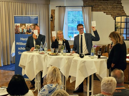 Die drei Kandidaten halten Zettel hoch
