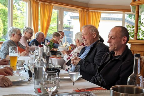 Mehrere Teilnehmer/innen zum Beginn des Schnitzelessens an der langen Tafel im Restaurant