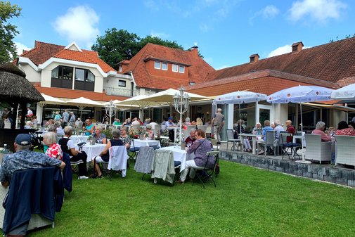 Die Gästen an den Tischen im Garten