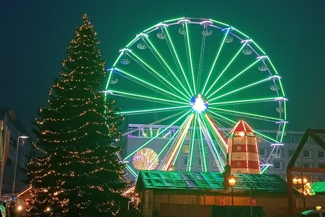 Weihnachtsmarkt mit Riesenrad und beleuchtetem Weihnachtsbaum