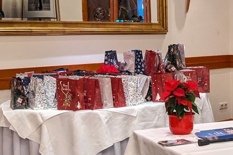 Für jede Teilnehmerin und jeden Teilnehmer wurde ein farbige Weihnachtstüte mit Überraschungen gepackt. Vor der Veranstaltung stehen sie aufgereiht auf einem Beistelltisch.