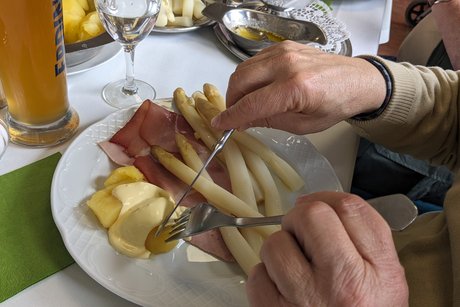 Ein Teller mit Spargel, Schinken und Kartoffeln.