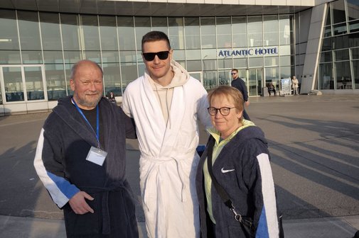 Die drei Personen im Bademantel l&auml;cheln in die Kamera