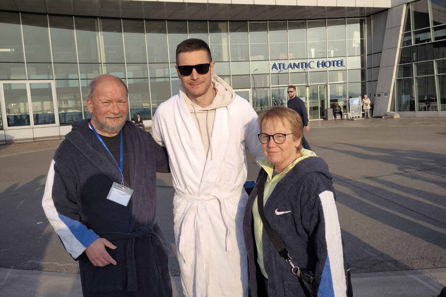 Die drei Personen im Bademantel l&auml;cheln in die Kamera