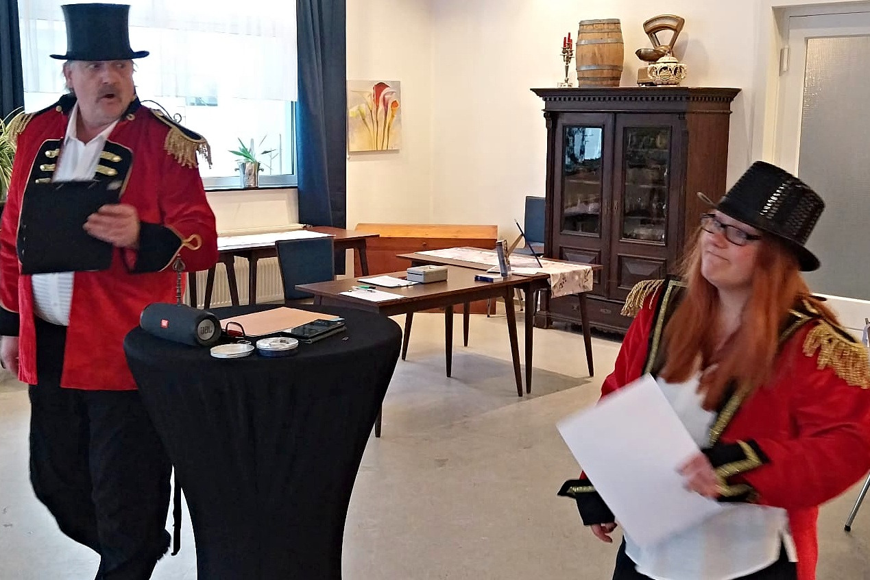 Büttenrede Auf dem Foto sind Bernadette Wolski und Matthias Krüger zu sehen, die als Zirkusdirektorin und Zirkusdirektor verkleidet sind. Beide tragen rote Jacken mit goldenen Schulterstücken. Außerdem haben sie einen Zylinder auf dem Kopf.