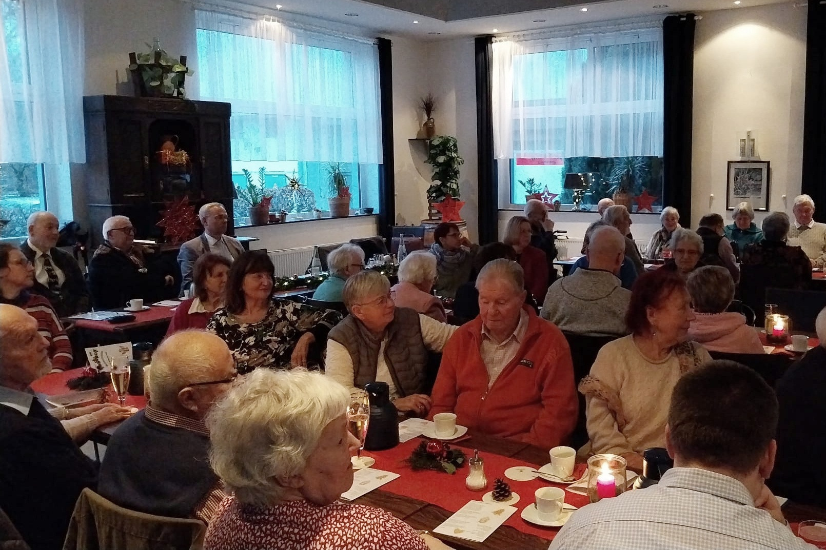 Auf dem Foto sind die G&auml;ste unser Weihnachtsfeier zu sehen, die an festlich gedeckten Tischen sitzen und der Begr&uuml;&szlig;ungsrede des OV-Vorsitzenden zuh&ouml;ren.