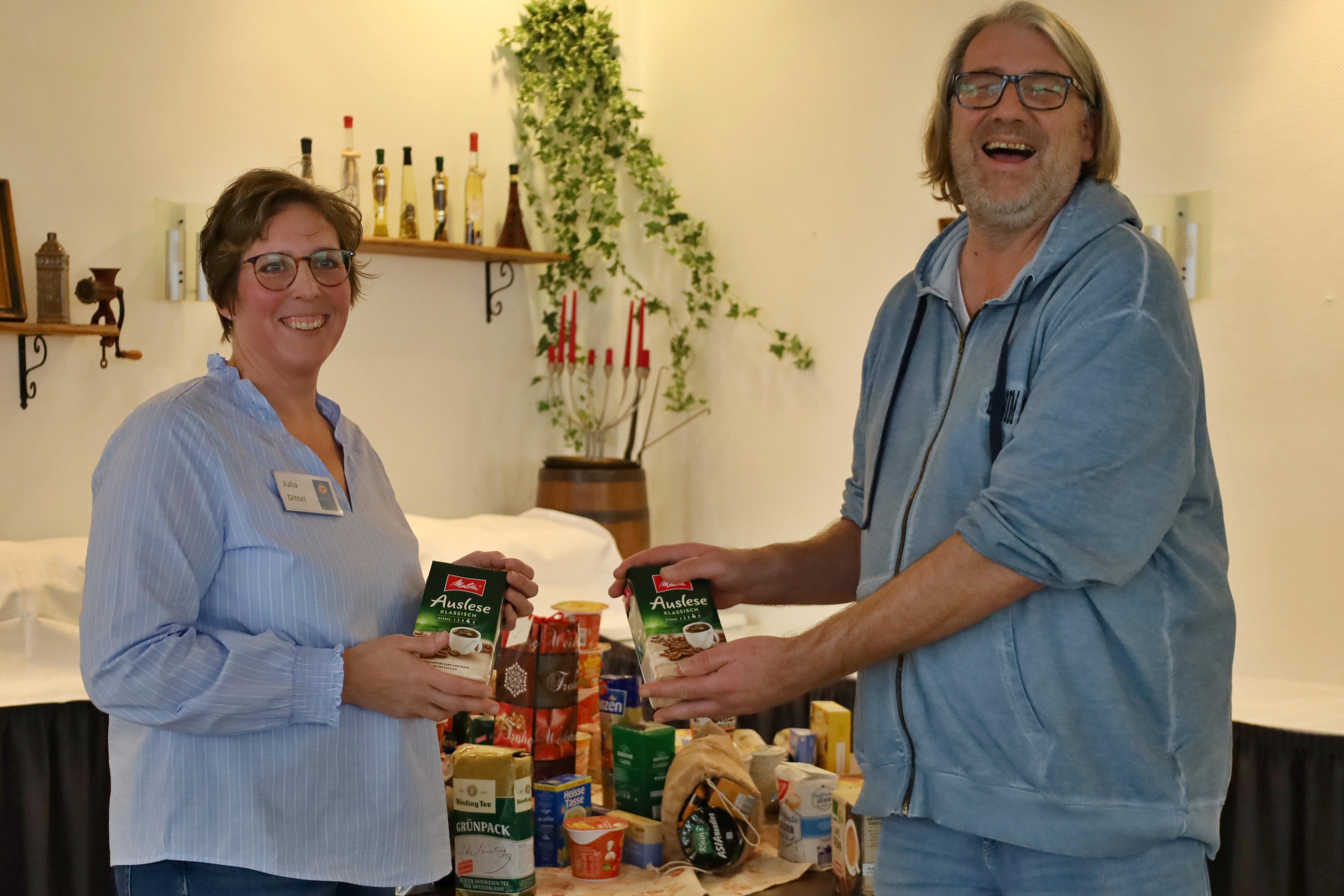 Auf dem Foto stehen Frau Julia Dittel von der Bahnhofsmission Celle und Matthias Kr&uuml;ger vor einem Tisch, auf dem Spenden stehen, die die Teilnehmerinnen und Teilnehmer unseres monatlichen Treffens f&uuml;r die Bahnhofsmission gesammelt haben.