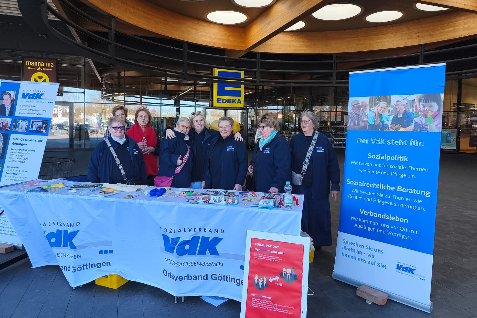 Hinter dem Stand des VdK stehen Vorstandsmitglieder in dunkelblauen Jacken mit VdK Aufdruck