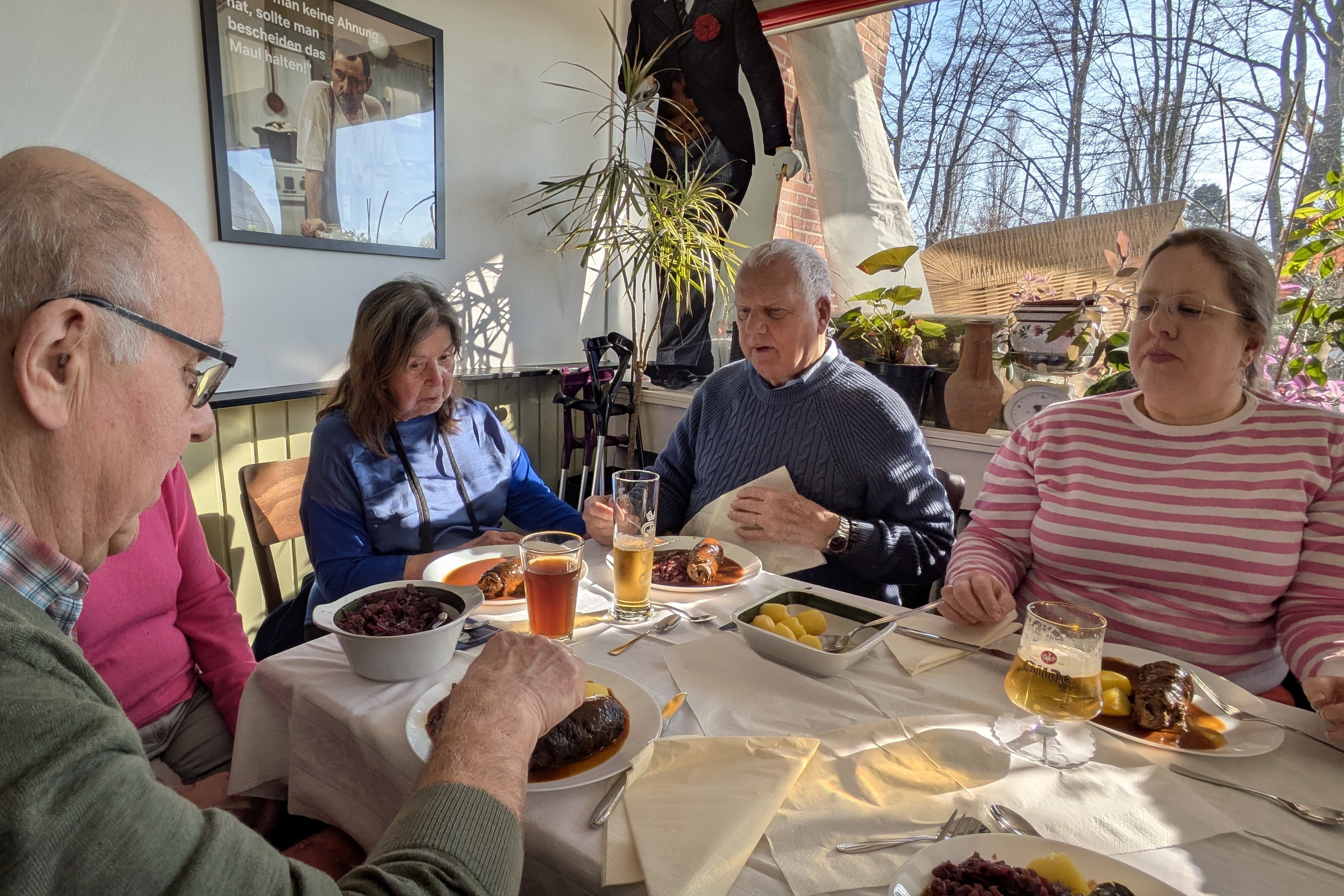 Das Bild zeigt vier Personen an einem Tisch, die gemeinsam Rouladen essen.